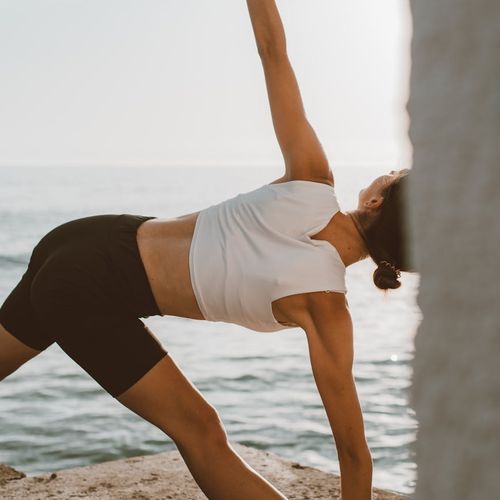 Person stretching outdoors during a sunrise, feeling energized.